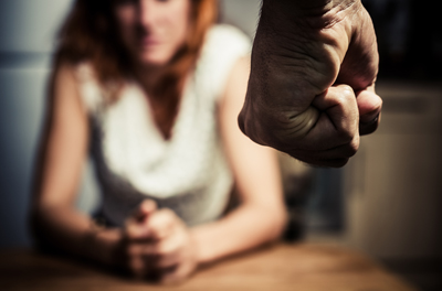 Man's fist in foreground and woman lookig at it in the background