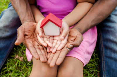 man and girl both hands open with a small house sitting in their hands