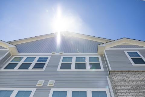 The Sullivan, a new grey three story apartment building on a sunny day with clear blue skies in the background.