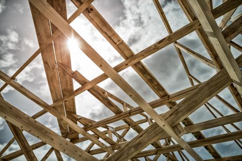 The framing of a roof in the foreground with a cloudy sky pierced by an afternoon sun in the background.