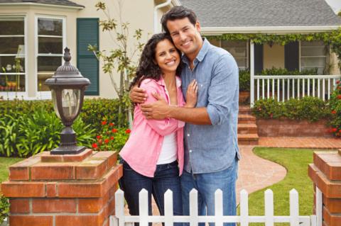 Woman on the left, man on the right, embracing in front of their home.